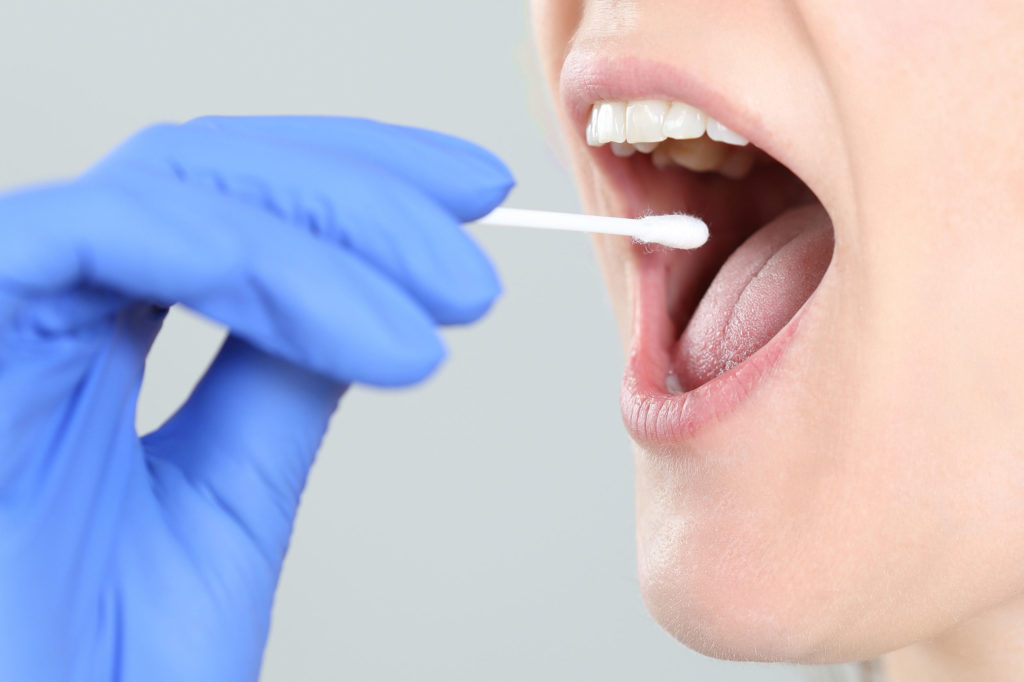 A woman with a cotton stick near her mouth to test for THC through saliva